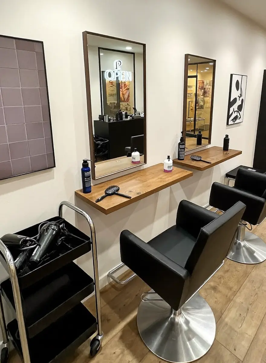 Frisierstühle vor Holzablage und Spiegeln im Salon